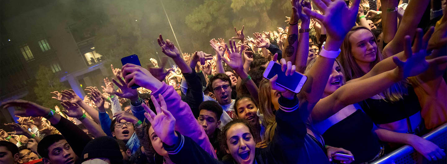 UC San Diego students cheer in front of a nighttime concert stage