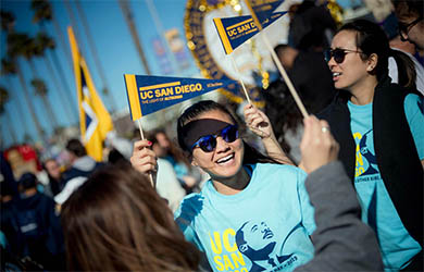 UC San Diego students march in the annual Martin Luther King Jr parade - smiling and holding UC SAN DIEGO pennants