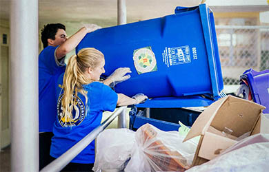UC San Diego students participate in a day of service - two students empty a large trash bin