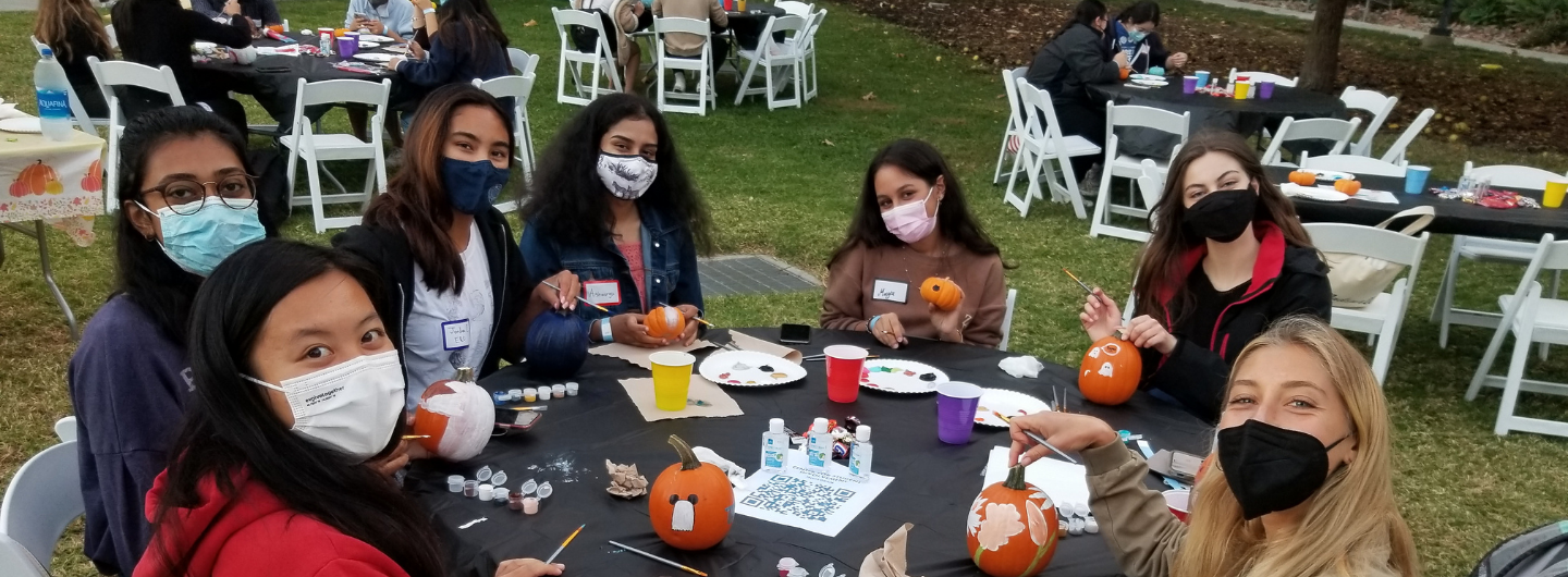 2 of 5, second year students painting pumpkins at a table