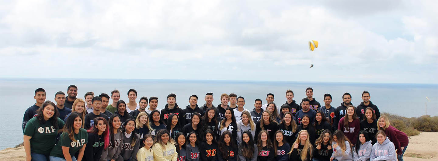 A large group of UC San Diego students poses at the beach