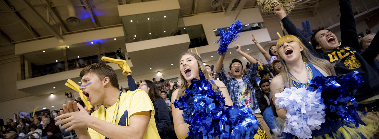 UC San Diego students cheer in RIMAC auditorium, dressed up in blue and gold Triton spirit gear